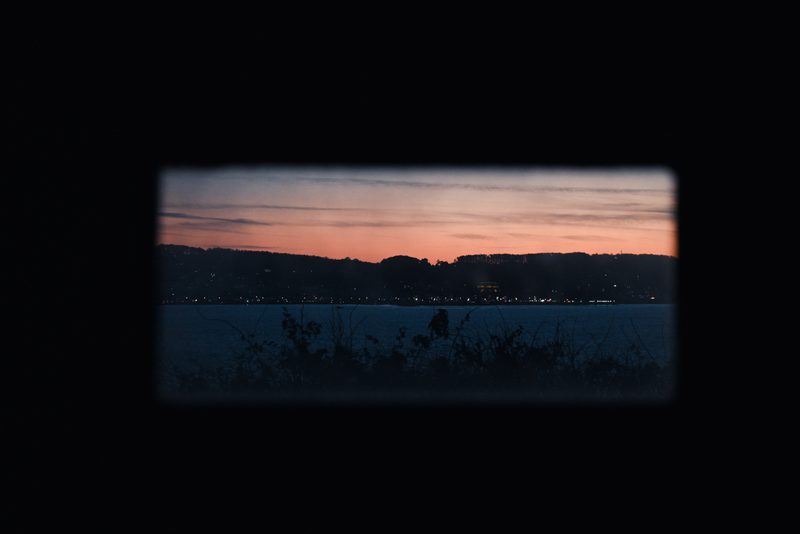 Sunset over the bay framed by a dark window