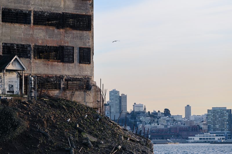 Ruined cell block wall with the city skyline behind