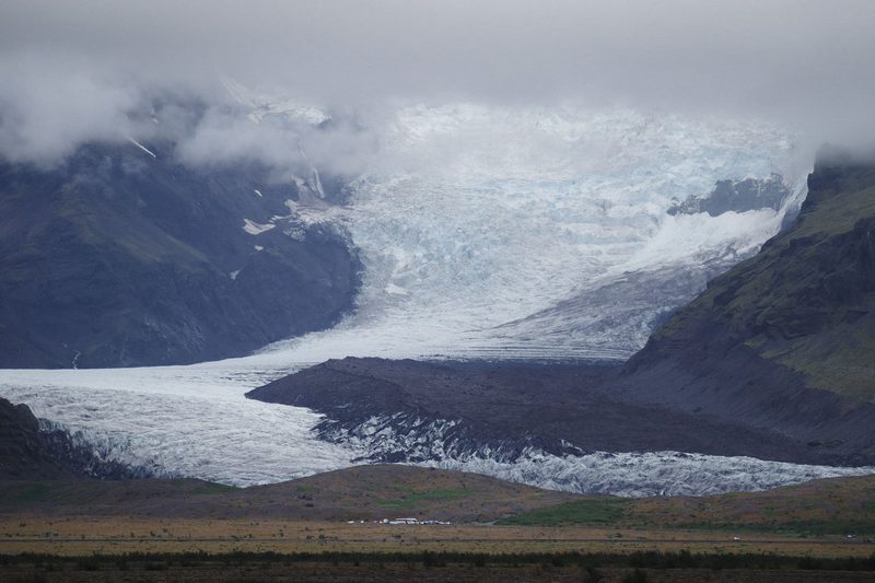 Glacier tongue flowing down between dark mountains